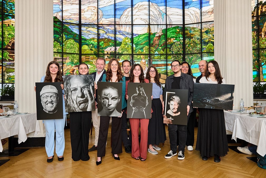Gruppenfoto der Preisträger:innen des Bundesnachwuchswettbewerbs 2026 vor dem Glasfenster im Hotel Herzoghof in Baden, mit ihren prämierten Werken.