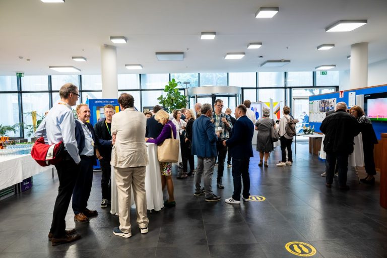 Blick ins Foyer: Gäste stehen in kleinen Gruppen zusammen, im Hintergrund die Glasfront