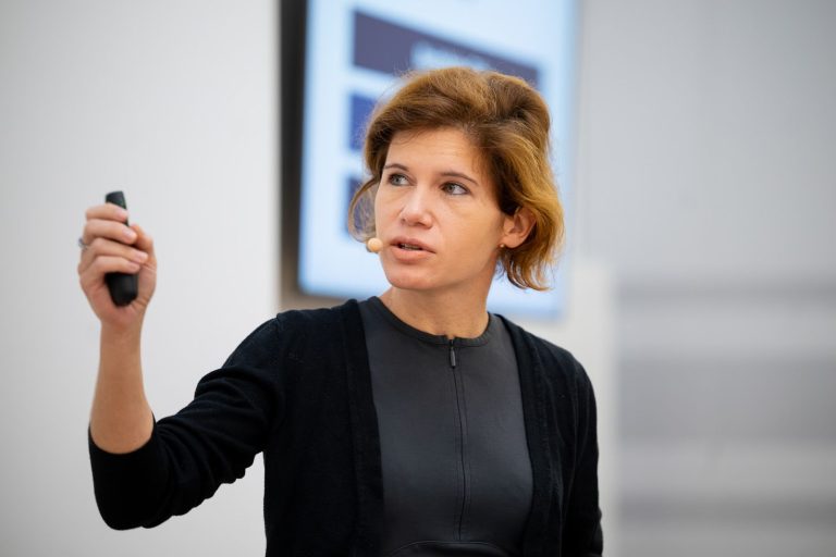 Vortragende mit Headset und Presenter spricht zum Publikum