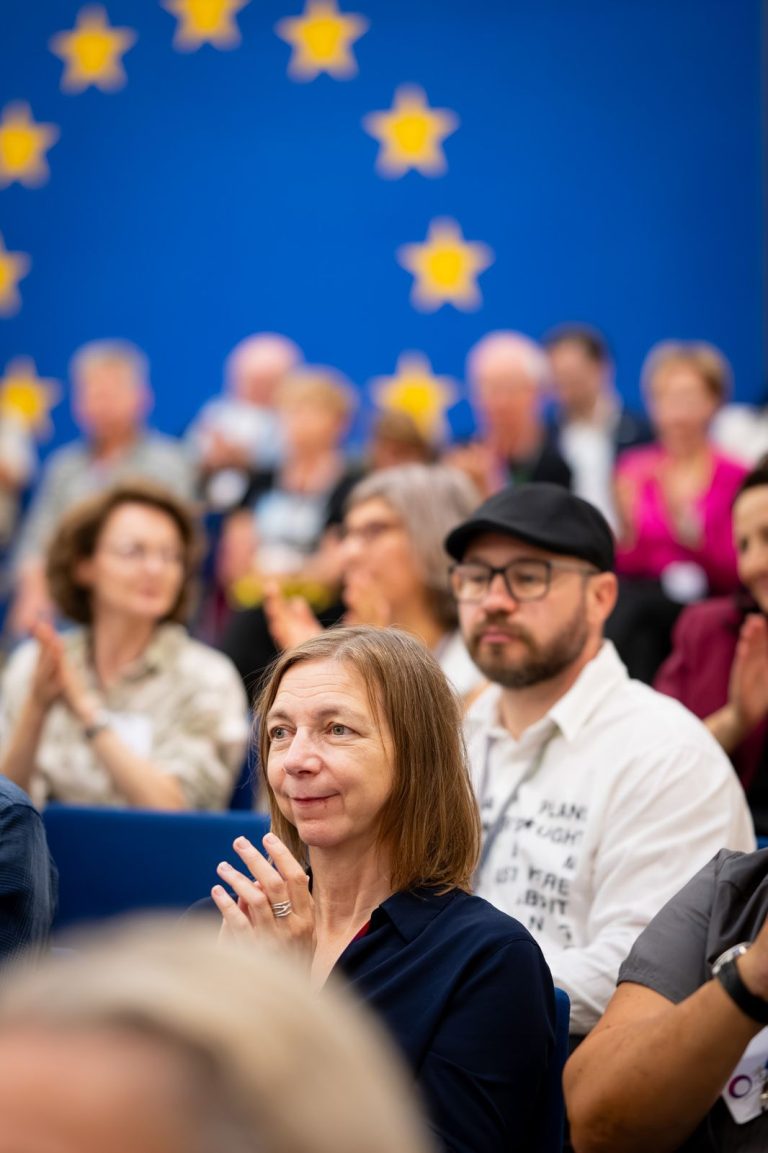 Applaudierende Gäste im Publikum vor dem EU-Sternenkreis