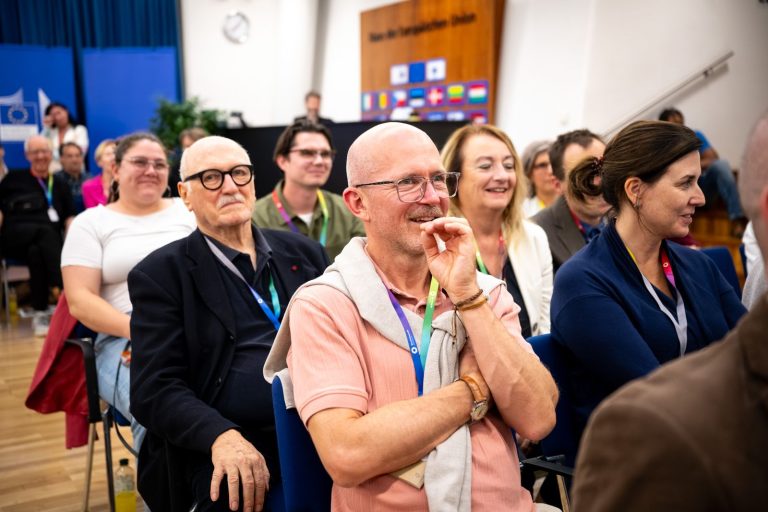 Gäste im Publikum lachen, ein Mann hält sich die Hand vor den Mund