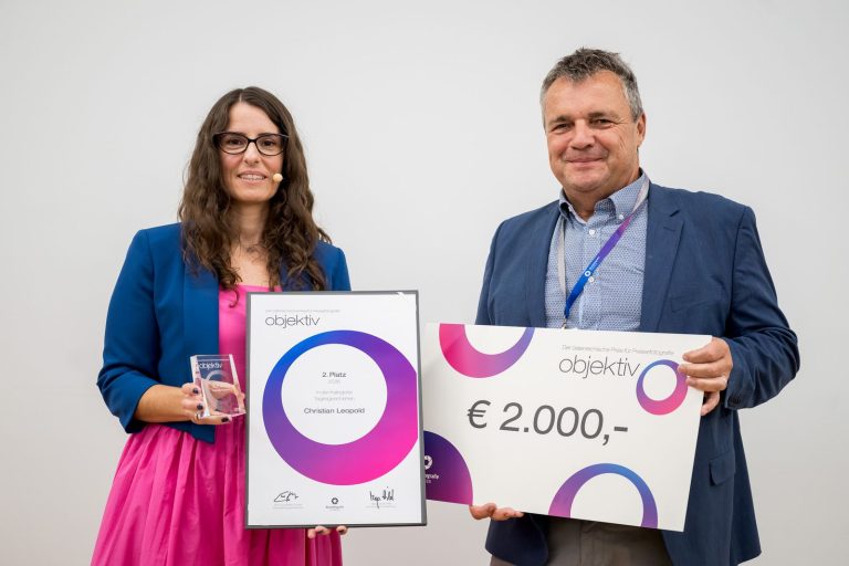 Preis Tagesgeschehen, 2. Platz für Christian Leopold: Die Moderatorin hält Urkunde und Trophäe, ein Mann den Scheck über 2.000 Euro