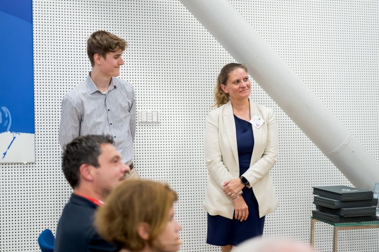 Junger Mann und Frau im hellen Blazer stehen am Rand des Saals
